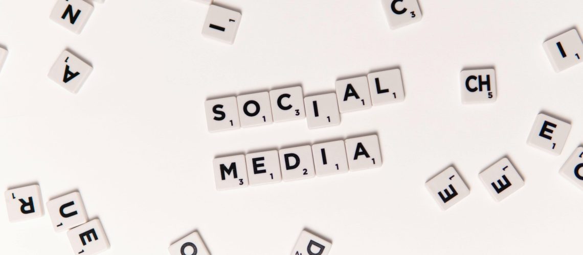 Flat lay of letter tiles spelling Social Media with scattered white tiles on a surface.