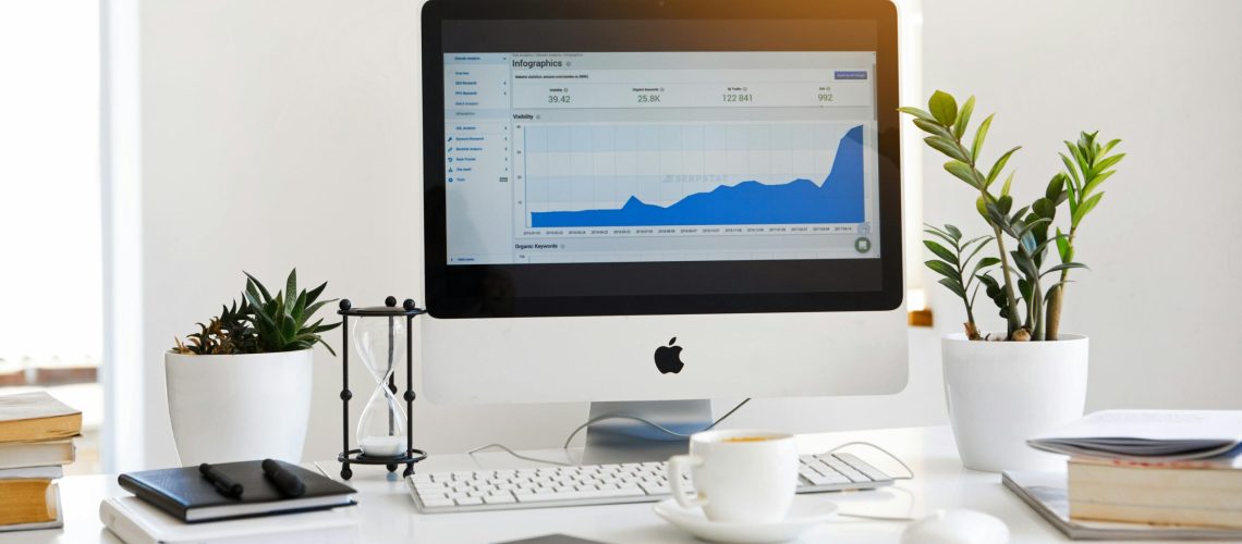 Silver Imac Displaying Line Graph Placed on Desk