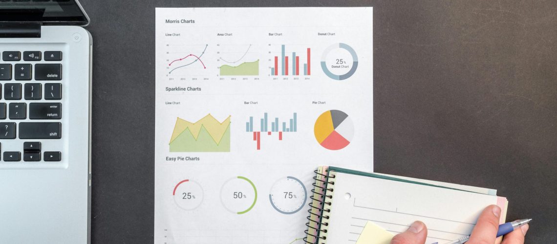 Overhead view of a business desk with charts and a laptop, ideal for data analysis concepts.