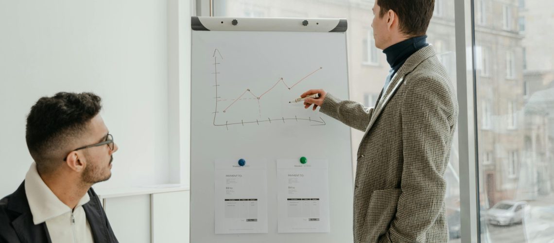 Two professionals examining graphs during an office presentation.