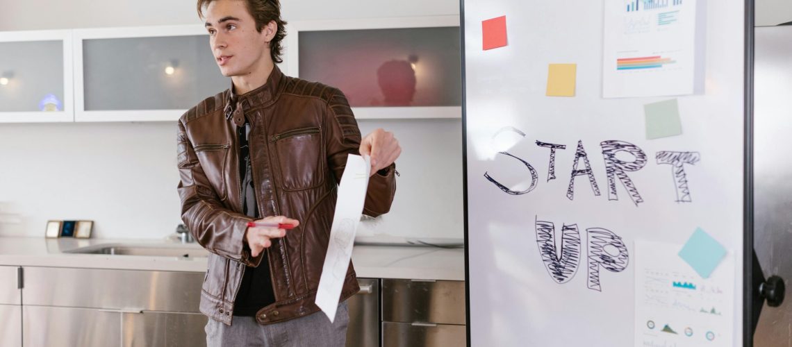 A young entrepreneur gives a presentation on startup strategies indoors with a flip chart.