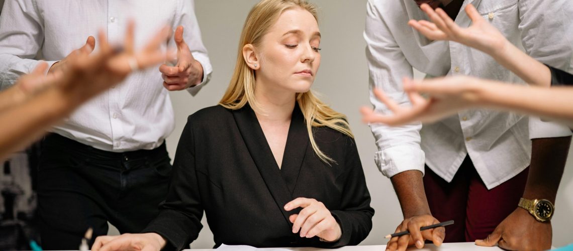 Team of professionals in a tense office discussion around a desk with documents.